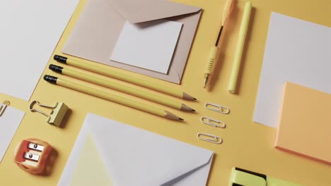 close up of pens, pencils and stationery arranged on yellow background, in slow motion