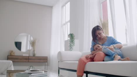 madre e hijo usando tableta mirando la pantalla y hablando en el sofá en una casa acogedora