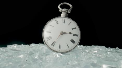 a vintage pocket watch resting on shattered glass
