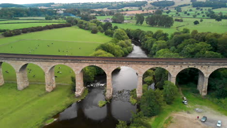 Drohnenflug-Entlang-Des-Viadukts-über-Einen-Wunderschönen-Langen-Fluss-Und-Eine-Grüne-Landschaft-In-Yorkshire