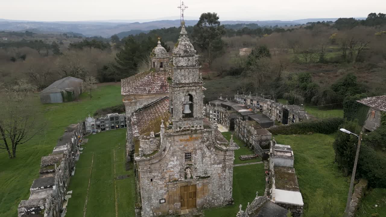 el dron orbita alrededor de la torre del campanario y el techo cubierto de musgo con césped bien cuidado en la iglesia de santa maría de salamonda en san amaro, españa.