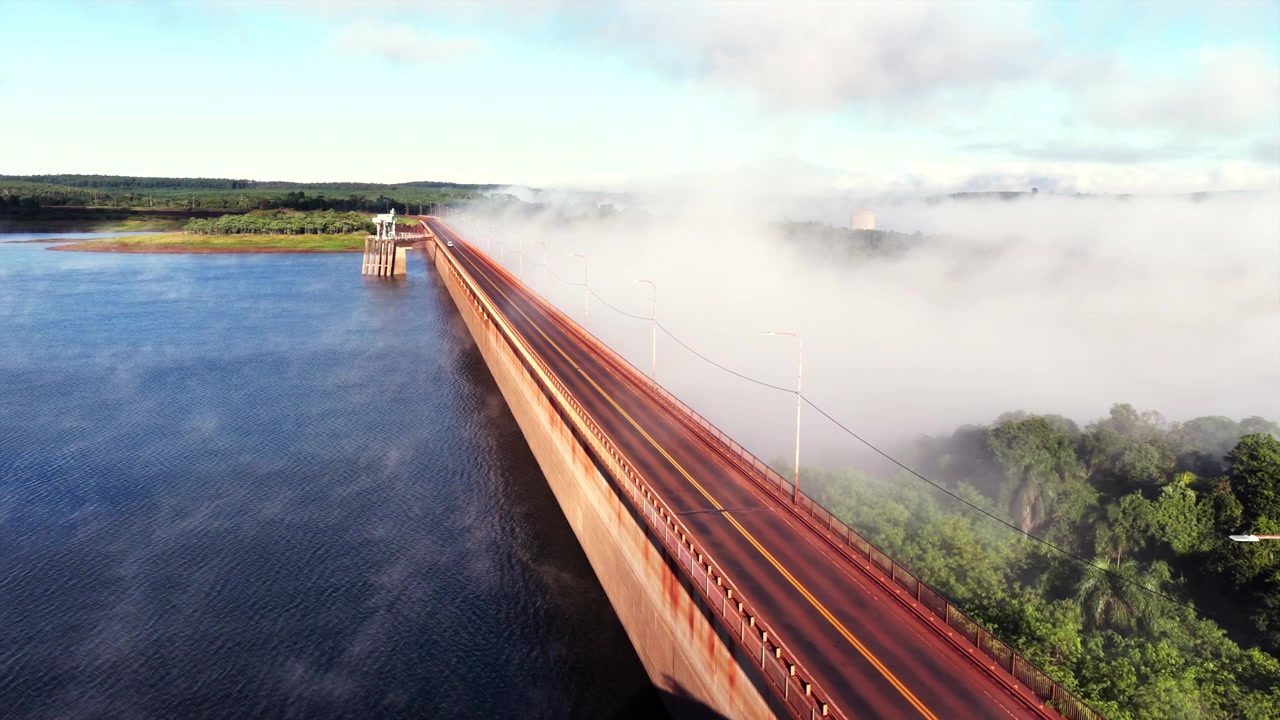 La diga di Urugua-i attraversa il bacino idrico di Urugua-i sul fiume Urugua-i vicino a Comandante Andresito, General Manuel Belgrano, Misiones, Argentina, circondata dalla Foresta Atlantica e da una fitta nebbia mattutina, sorvolo con drone