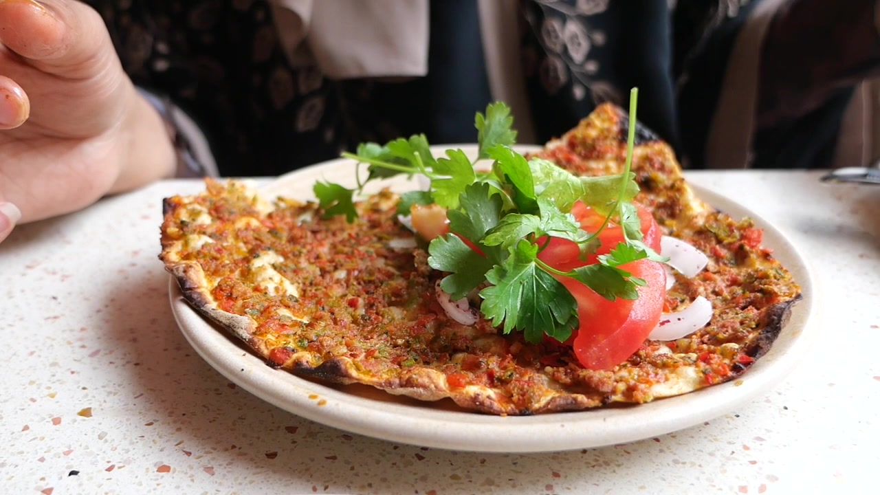 Person Garnishing Lahmacun with Fresh Herbs