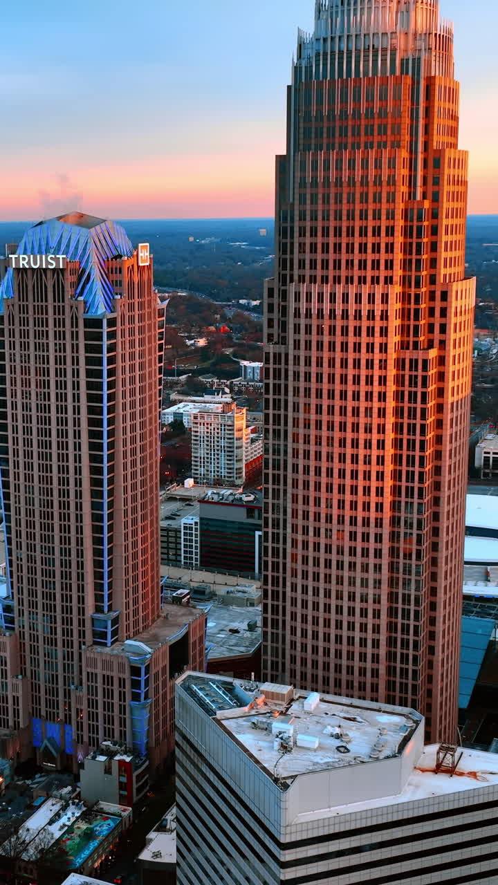 Facciate di bellissimi grattacieli alla luce arancione del tramonto. In lontananza, un edificio a molti piani a Charlotte, Carolina del Nord, USA