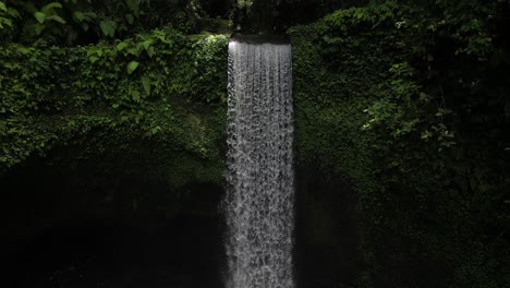 Tibumana-Waterfall-in-Bali-on-a-sunny-morning,-with-jungle-environment,-aerial