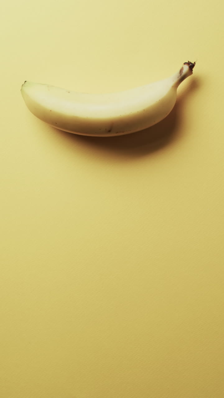 Vertical video of banana with copy space over yellow background