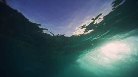 light rays sparkle on sand under breaking wave crashing with vortex