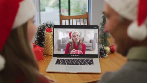 Happy-caucasian-senior-couple-on-video-call-with-female-friend-at-christmas-time