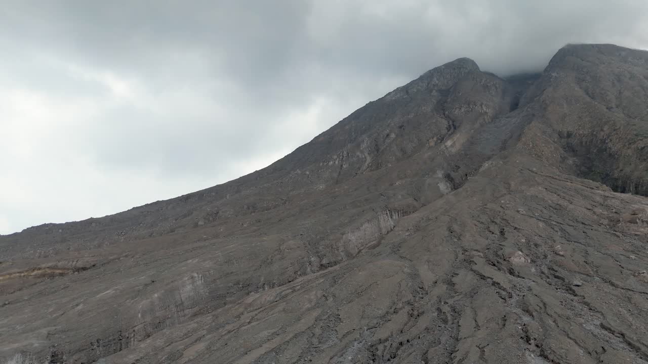 Aerial perspective of barren and rugged terrain on sides of Mount Sinabung