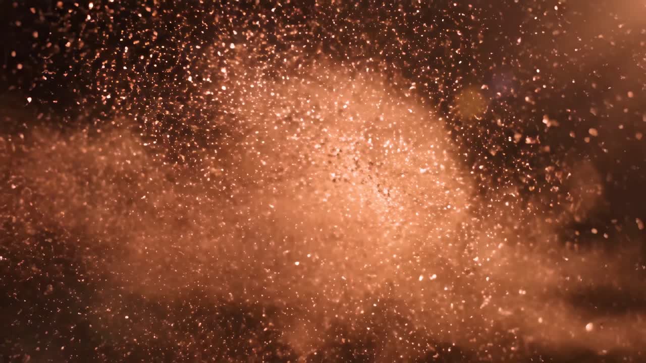 Particelle di glitter dorate che esplodono su uno sfondo scuro