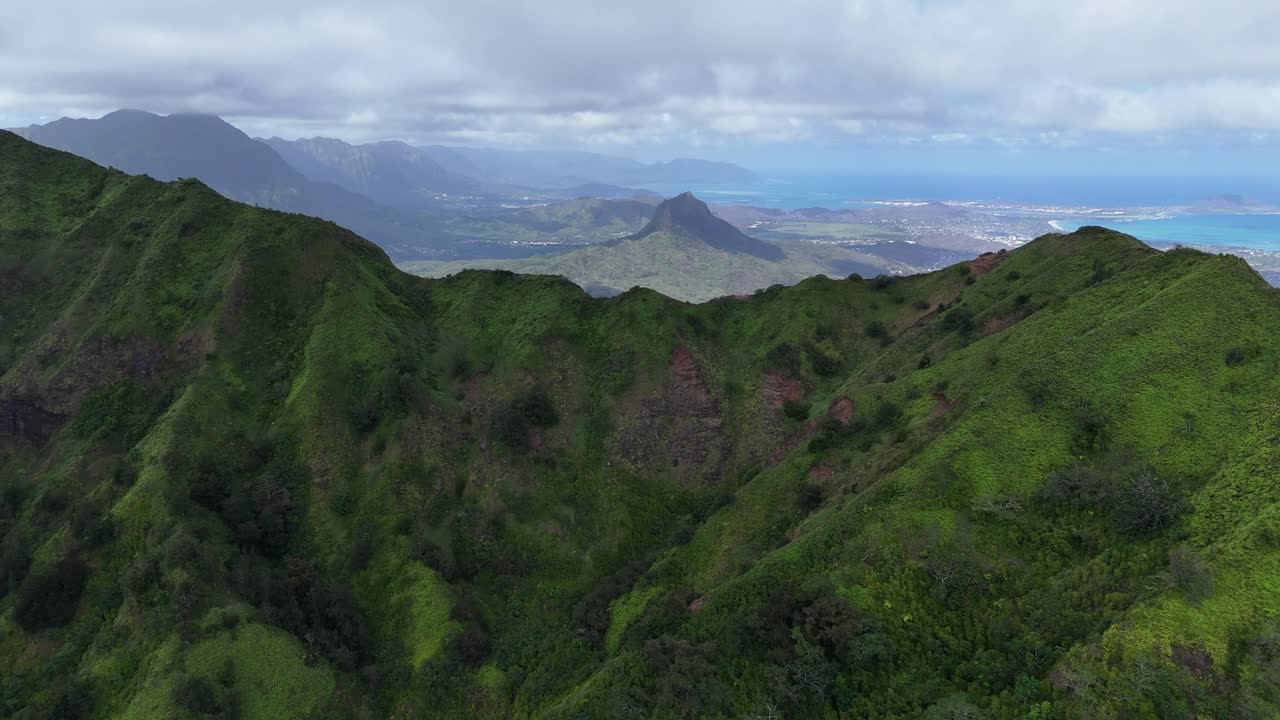 Vista aerea con drone di Oahu, Hawaii, sopra rigogliose montagne di foresta tropicale. Vista sul mare e sull'oceano in lontananza, filmato aereo cinematografico, destinazione di viaggio