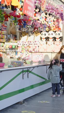 people at a carnival game booth with stuffed animal prizes