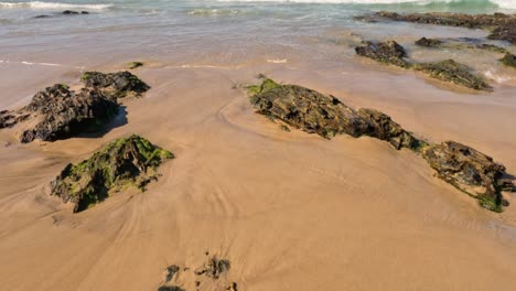 waves gently washing over rocks on sandy beach