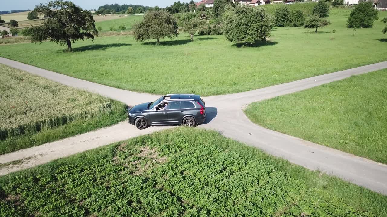 un camión suv volvo xc 90 gira en una intersección entre dos caminos cerca de campos agrícolas, campo, suiza, vaud, vista aérea de drones