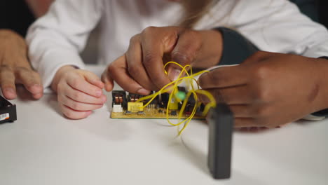 technician teaches girl to connect wires with probes to chip