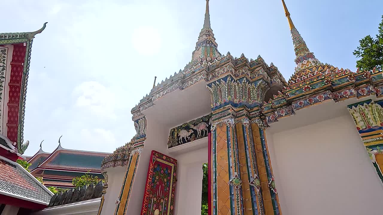 A visitor explores the ornate architecture of Wat Pho under bright daylight, capturing the temple's intricate details and vibrant colors