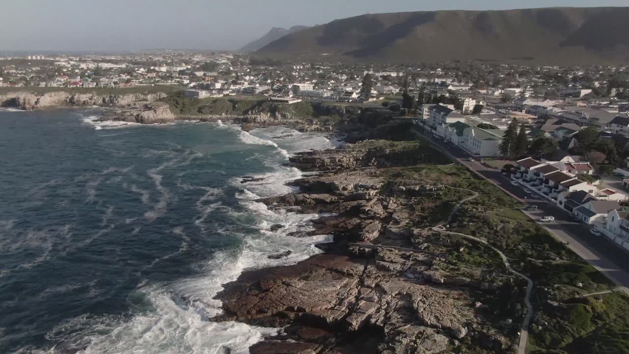 Olas espumosas rompiendo contra la costa rocosa durante el verano en Sudáfrica - toma aérea con dron