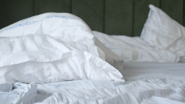 Primo piano di un letto bianco con cuscini e lenzuola a righe