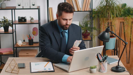 rich businessman in suit working on laptop pc counting money cash calculate earnings income profit