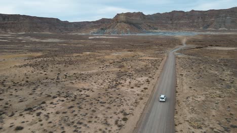 Drone-Vuela-Sobre-Un-Automóvil-Que-Conduce-A-Través-De-Una-Montaña-Humeante-Hacia-El-Punto-Alstrom,-Lago-Powell