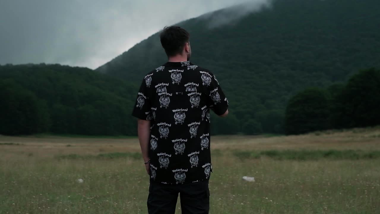 Slow-motion of a guy smoking and enjoying views of mountains during a cloudy day.