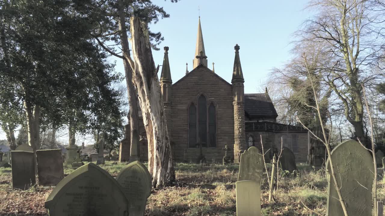Landlig engelsk landsbykirke i skovområde, skjult af træer i landskabet ved solopgang