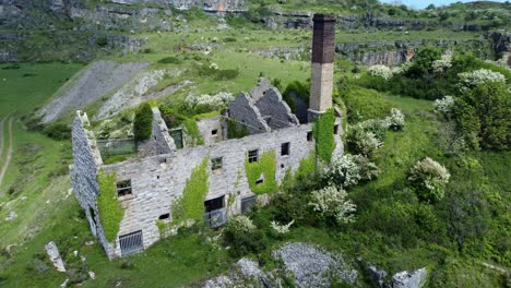 abandoned overgrown ivy covered desolate countryside historical welsh coastal brick factory mill aerial view rising right orbit