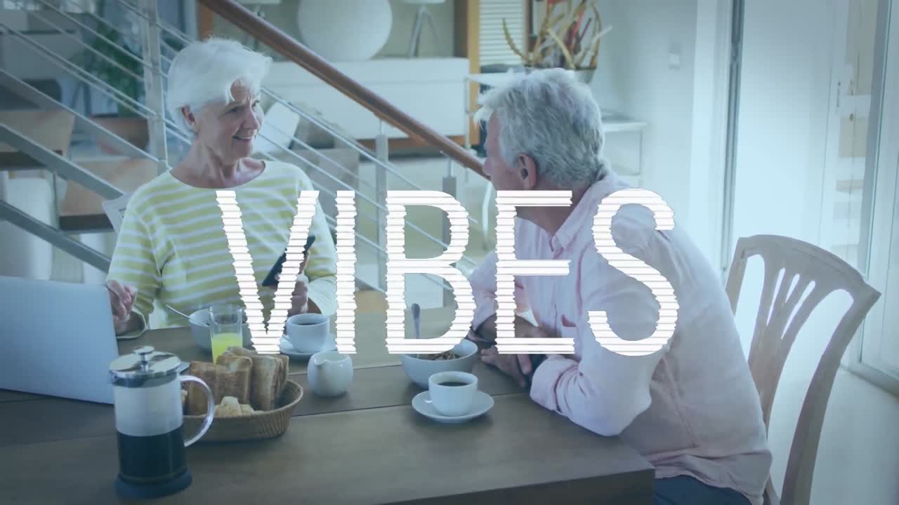Animation du texte "vibes" en blanc sur un couple de personnes âgées caucasiennes heureux utilisant un ordinateur portable au petit-déjeuner