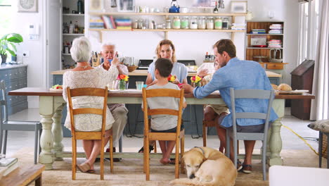 tres generaciones de la familia comiendo en la mesa de la cocina en casa