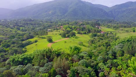 Cinematic-aerial-flight-over-green-rainforest-and-Dominican-Alps-in-background