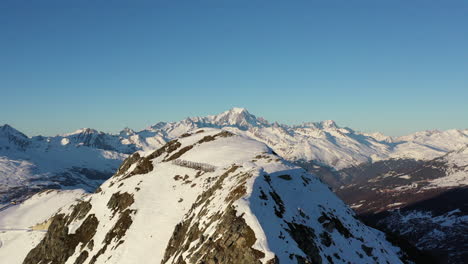 無人機射擊追蹤右向左顯示雪覆蓋的山峰,冬天晴天背景是白山