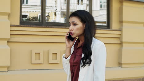 stressed businesswoman walking outdoors. young woman using phone outside