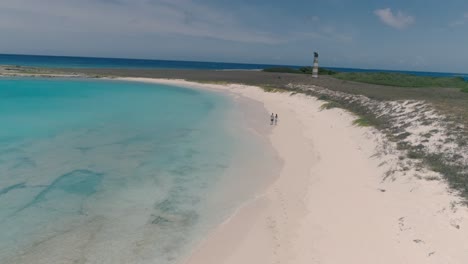 pareja camina sobre arena blanca hacia el faro, cayo de agua los roques venezuela