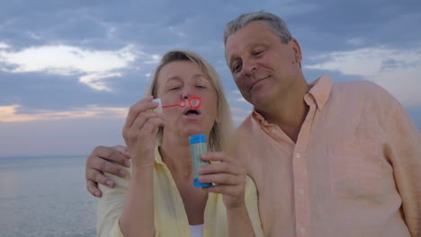 una pareja feliz soplando burbujas en la playa.