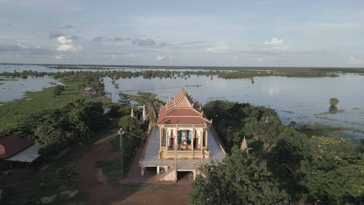 Golden-roofed temple stands on dry land amid vast flooded plains in Tonlé Sap’s serene landscape