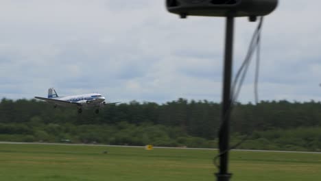 silver and blue douglas dc3 taking off the runway at baltic international airshow, view from the ground, handheld 4k shot