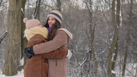 front view of mother and daughter in winter clothes hugging in a snowy forest 1