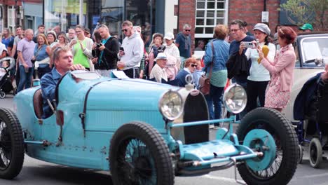 classic car driving through a crowded street