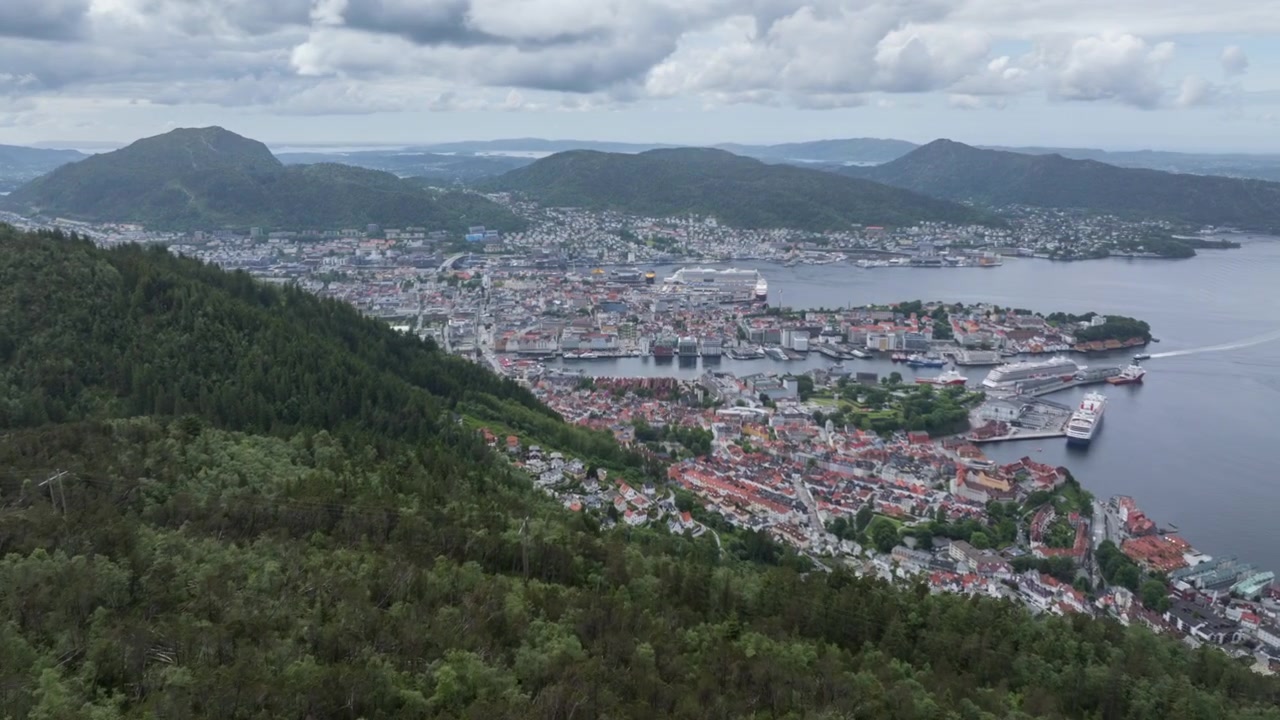 Drone-hyperlapse som flyr over Sandviksfjellet og avslører Bergen by under drivende sommerskyer.