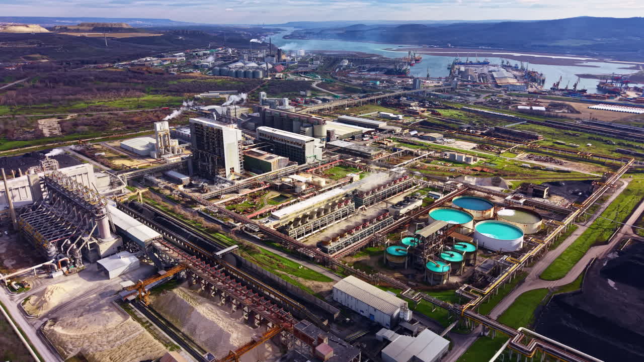 Vista de una zona industrial con fábricas, tanques de almacenamiento y maquinaria cerca de un río durante el día