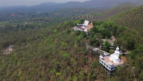hilltop buddhist temple overlooks chiang mai valley with trees and misty air, aerial pan