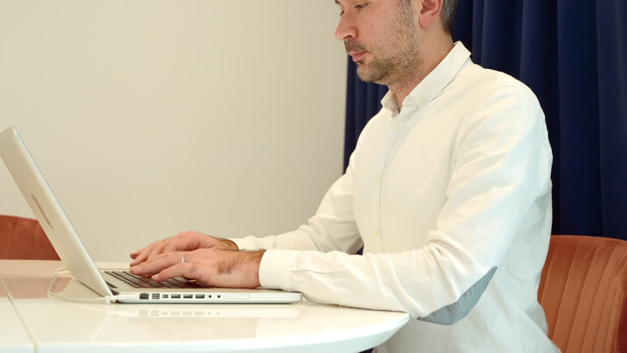 Man wearing white shirt working on notebook at home