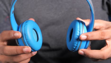 person holding blue headphones