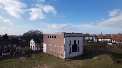 backwards aerial reveal showing surrounding of former youth prison facility, now abandoned waiting for demolition and refurbishment of the moated plot field in zutphen, the netherlands