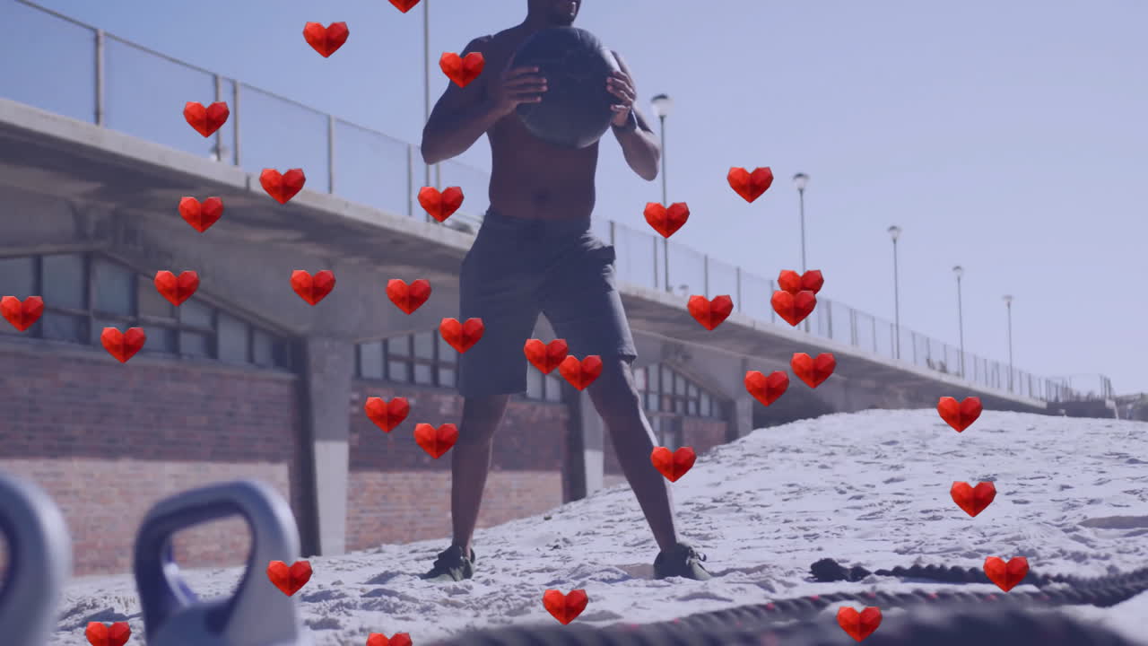 Exercising on beach, man with medicine ball and animation of red hearts