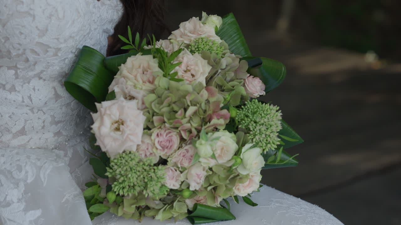 En betagende brud holder yndefuldt sin buket og fremviser skønheden i hendes blomsterarrangement på hendes særlige dag.