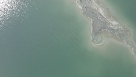 aerial rotating pull up top down shot of salt shore estuary in the dead sea israel, drone shot