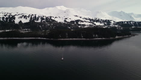 Toma-De-Drone-De-Un-Velero-Frente-A-Las-Montañas-Nevadas-De-La-Isla-Montague,-Alaska