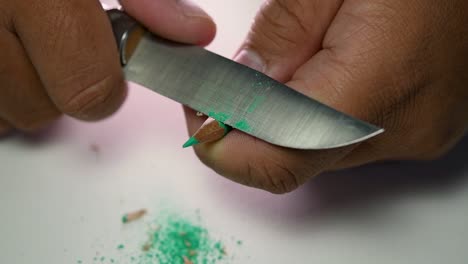 Footage-of-hands-slowly-sharpening-a-pencil-and-some-coloured-pencils-with-a-sharp-knife