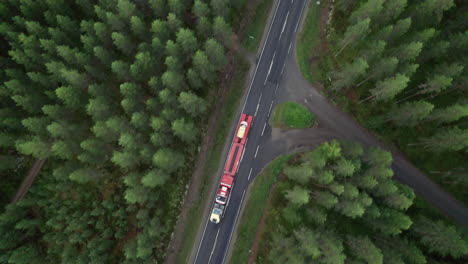 aerial bird view of forest road in finland, car porter truck passing by, car transportation, countryside, traffic, summer, overcast day